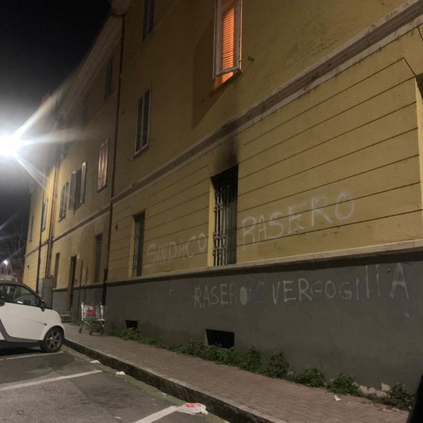 Un carrello sul marciapiede, portoni bruciati e una grossa (e sgrammaticata) scritta sul muro di un condominio: &quot;Rasero vergognIa&quot;