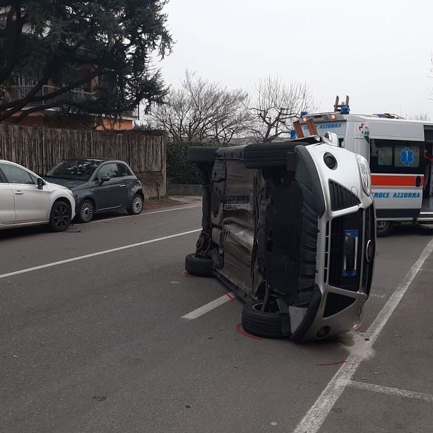Perde il controllo della macchina, urta un'auto in sosta e si ribalta